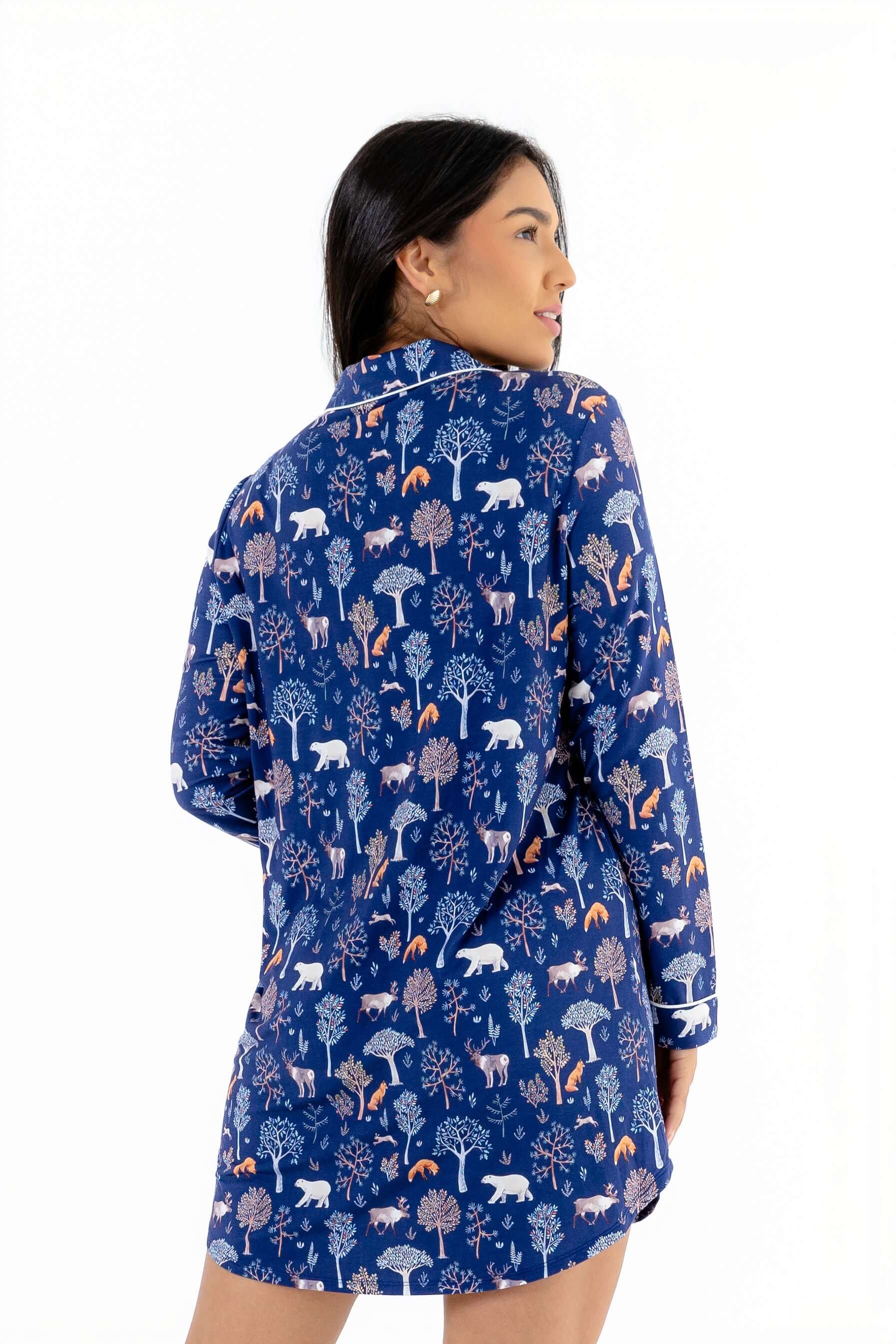 Model wearing the Woodland Night women's nightshirt long sleeve with a colorful forest print on a blue background.