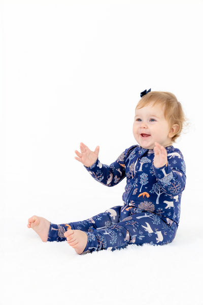 Side view of baby girl modeling Woodland Night baby modal pajama romper