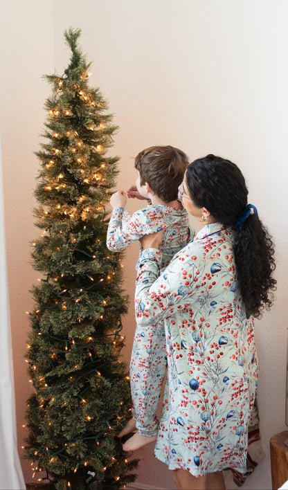 Two people in pajamas standing near a decorated Christmas tree in a bedroom.